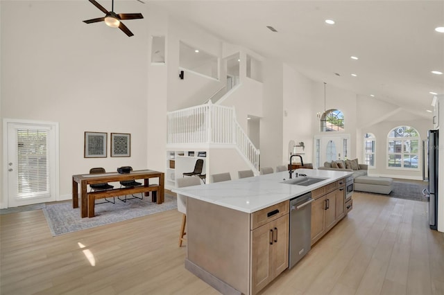 kitchen with high vaulted ceiling, light wood-type flooring, open floor plan, and dishwasher