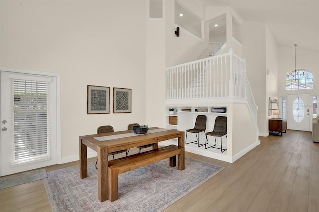 dining room featuring baseboards, high vaulted ceiling, a chandelier, and wood finished floors