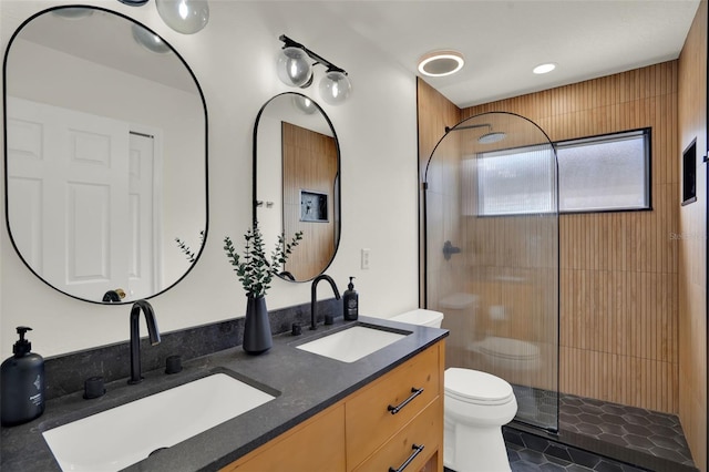 full bath with a sink, double vanity, toilet, and tiled shower