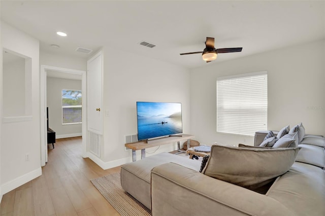 living room featuring baseboards, a ceiling fan, light wood-type flooring, and visible vents