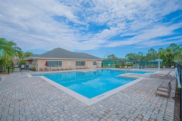 community pool with fence and a patio area