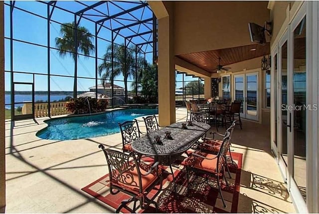 pool with a lanai, a ceiling fan, outdoor dining space, and a patio area