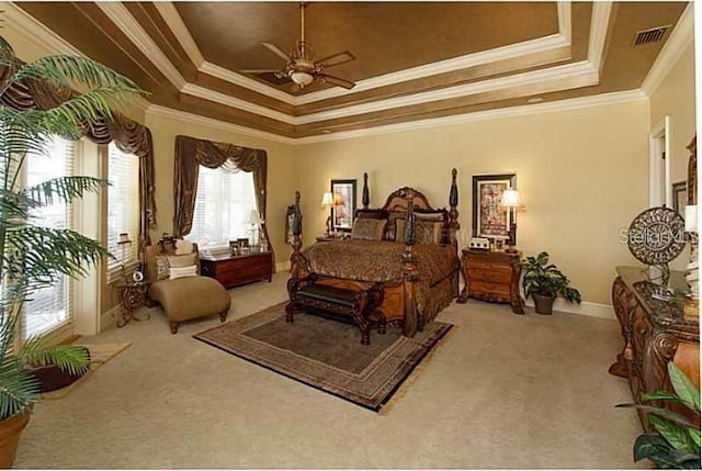 bedroom with baseboards, ornamental molding, a tray ceiling, and light colored carpet