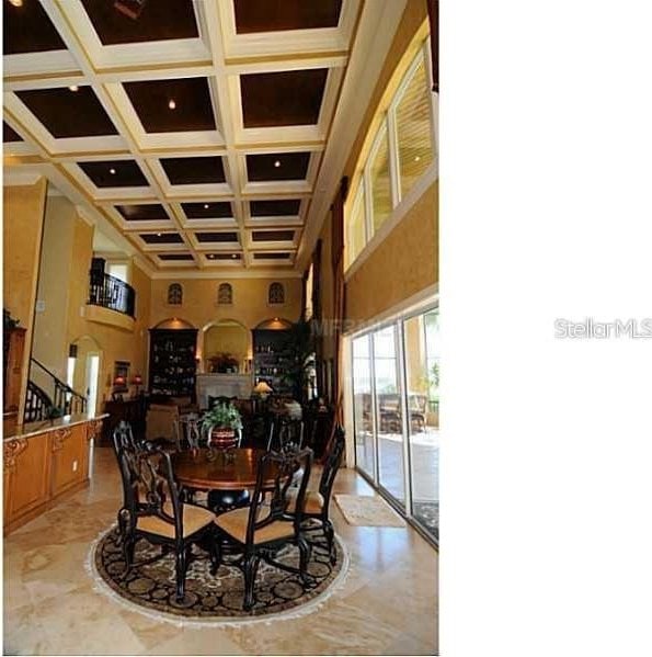 dining room featuring coffered ceiling and a towering ceiling