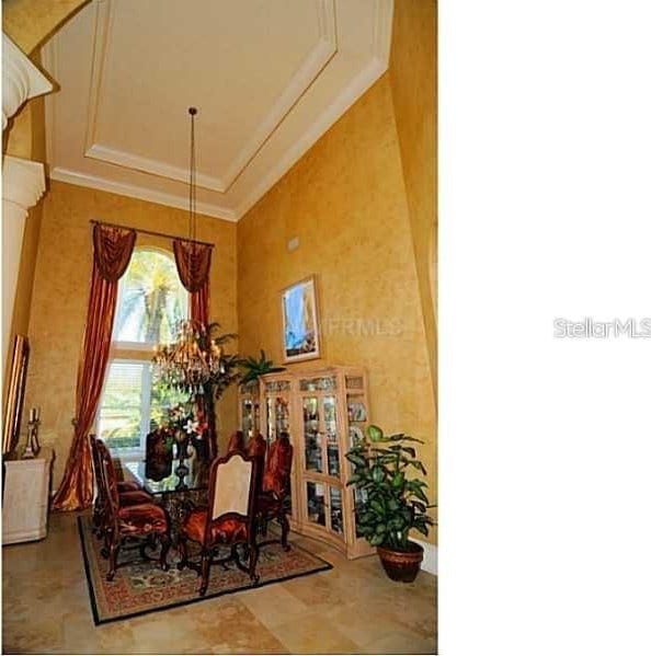 dining space with crown molding, a tray ceiling, an inviting chandelier, and a towering ceiling