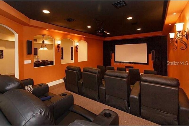 home theater room with recessed lighting, a raised ceiling, baseboards, and arched walkways