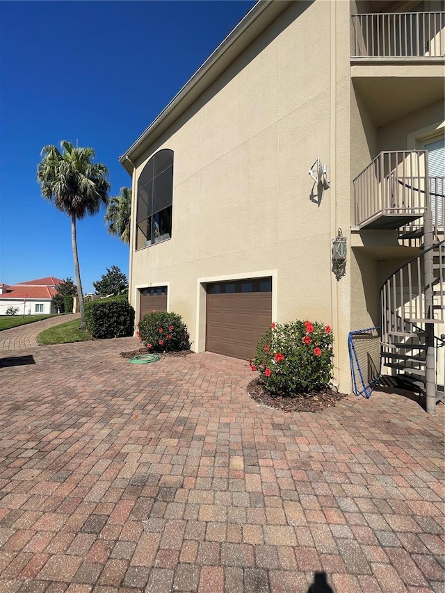 view of property exterior with stairs, stucco siding, an attached garage, and driveway