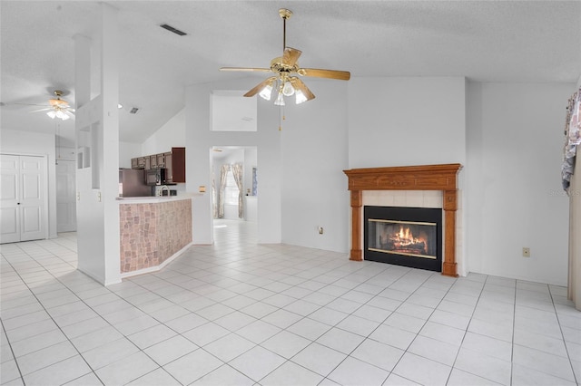 3137 Timucua Cir, Orlando, FL 32837 - unfurnished living room featuring a ceiling fan, a tile fireplace, high vaulted ceiling, light tile patterned floors, and a textured ceiling