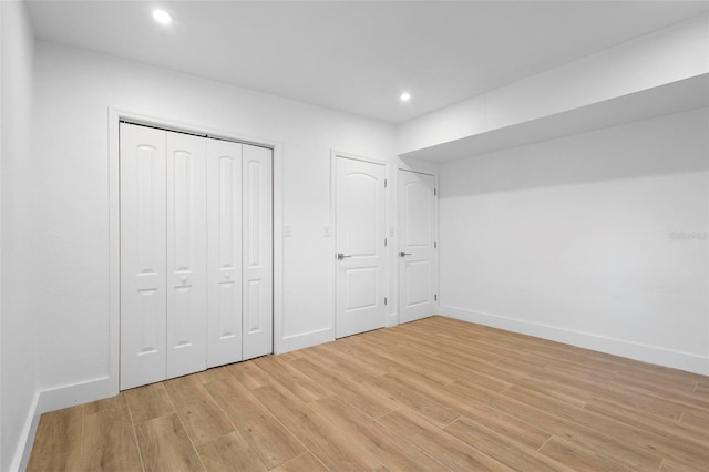 unfurnished bedroom featuring baseboards, a closet, light wood finished floors, and recessed lighting