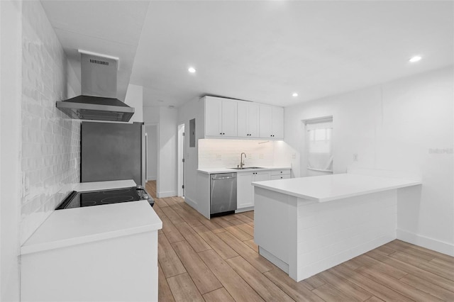 kitchen featuring wall chimney range hood, stainless steel appliances, light wood-type flooring, and a sink