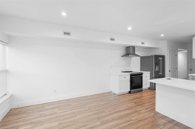 kitchen with high quality fridge, light countertops, black electric range oven, wall chimney range hood, and light wood-style floors
