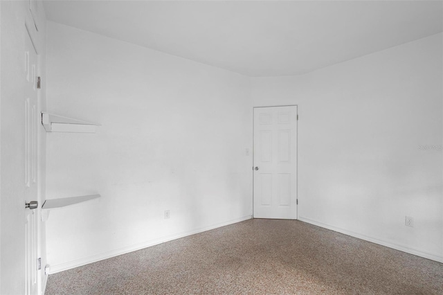 spare room featuring speckled floor and baseboards
