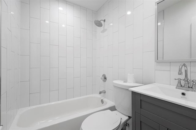 bathroom with toilet, tile walls, vanity, and bathtub / shower combination