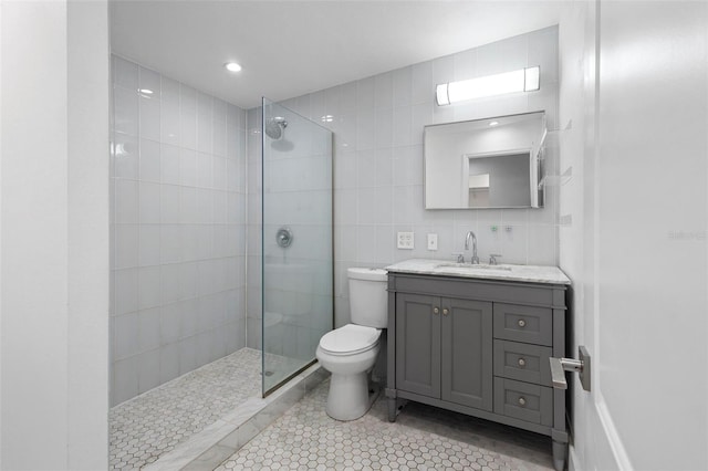 bathroom featuring a walk in shower, toilet, tile walls, and vanity