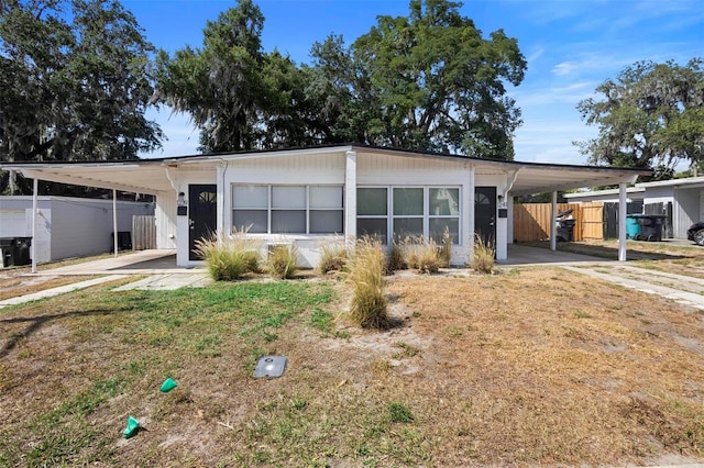 view of front of property featuring a front lawn, fence, and a carport
