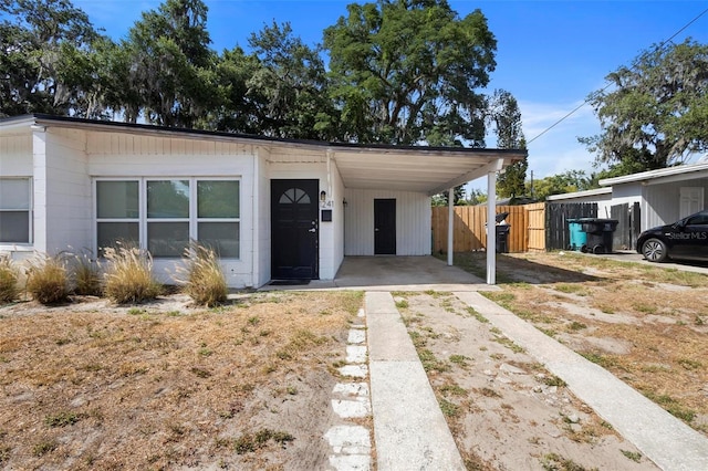 view of front of house with fence, dirt driveway, and an attached carport