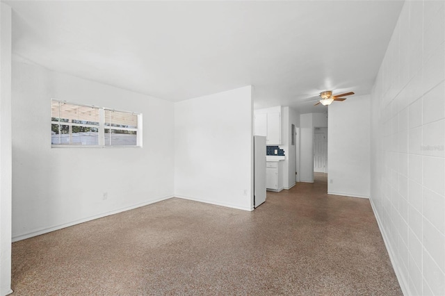 empty room featuring speckled floor, baseboards, and a ceiling fan