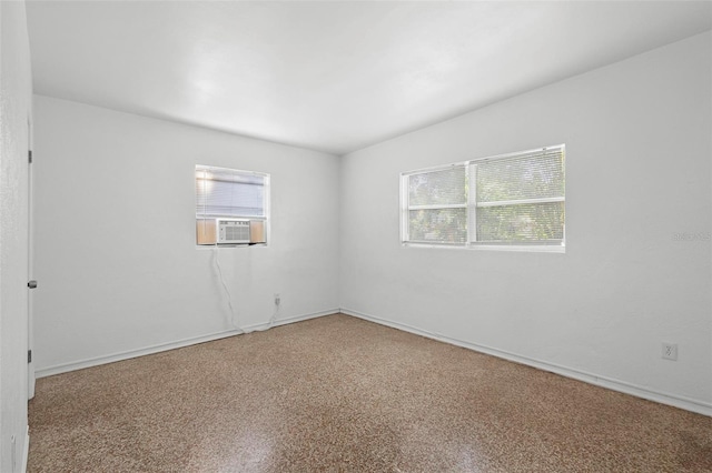 unfurnished room with baseboards and cooling unit