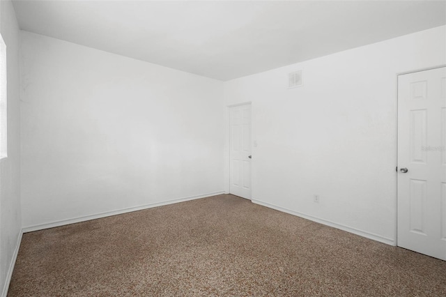 carpeted spare room with visible vents and baseboards