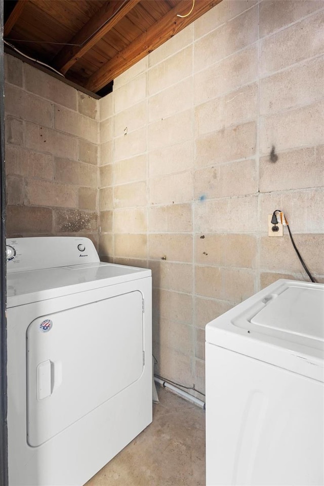 washroom featuring wood ceiling, laundry area, concrete block wall, and washer and dryer