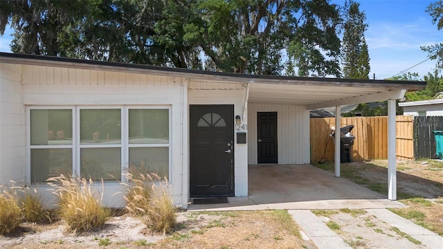 view of outdoor structure featuring driveway, fence, and a carport