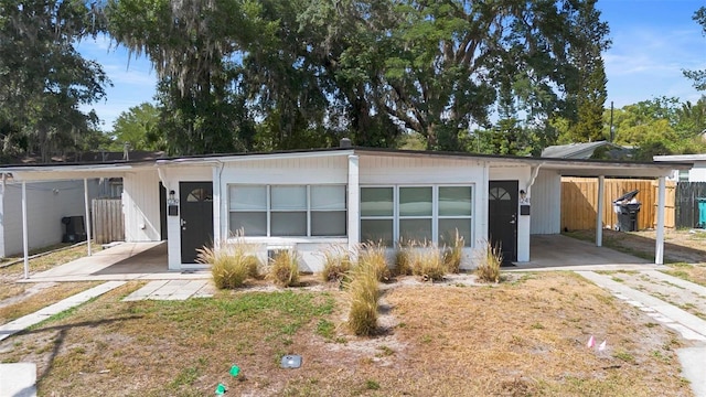 view of front facade with concrete driveway, fence, and a carport