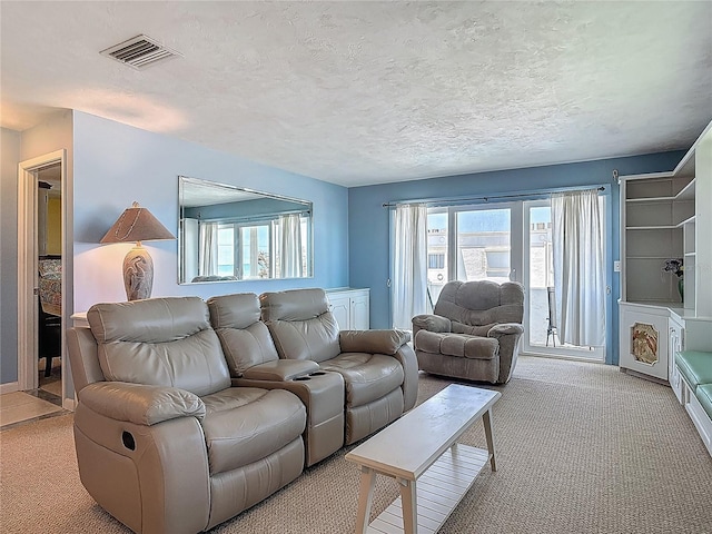 living area featuring visible vents, a wealth of natural light, and light colored carpet
