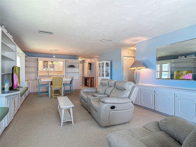 living area with visible vents and light colored carpet