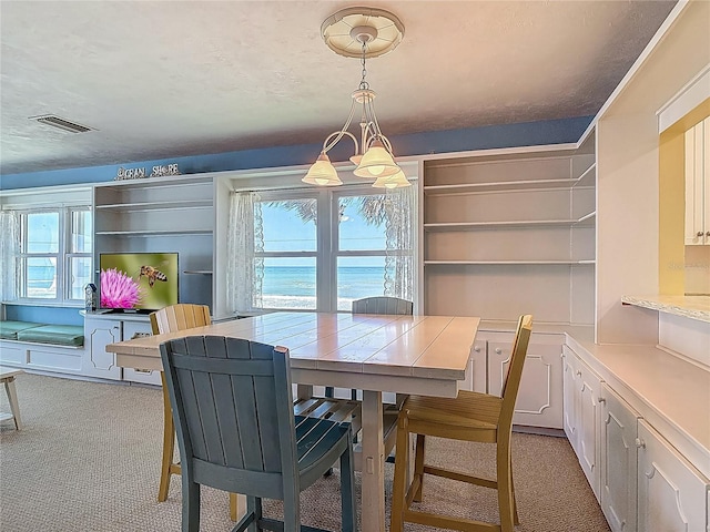 dining area with an inviting chandelier, light colored carpet, and visible vents