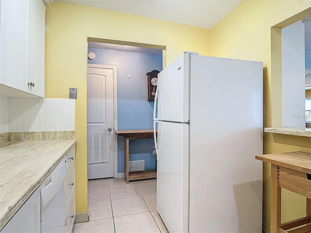 kitchen with white appliances, light tile patterned flooring, white cabinets, and light countertops