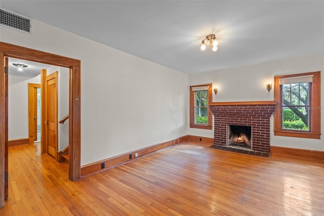 806 E Amelia St, Orlando, FL 32803 - unfurnished living room with baseboards, light wood-style floors, visible vents, and a brick fireplace