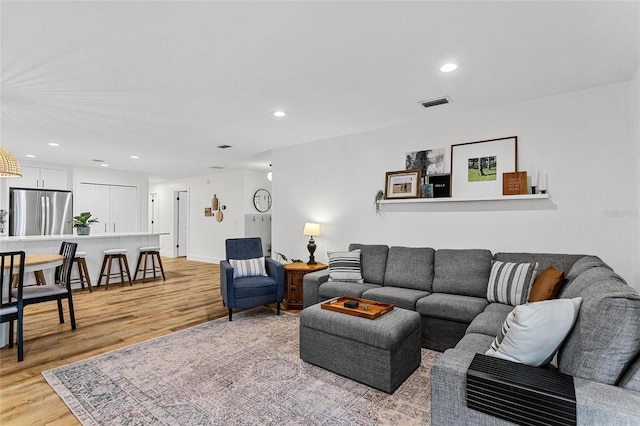 living room featuring recessed lighting, visible vents, and light wood-type flooring