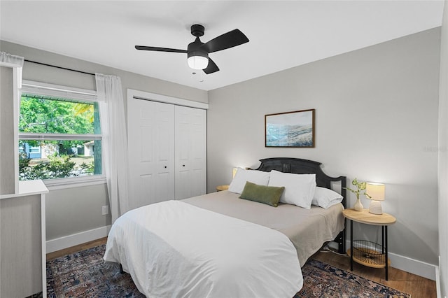 bedroom with baseboards, ceiling fan, a closet, and wood finished floors