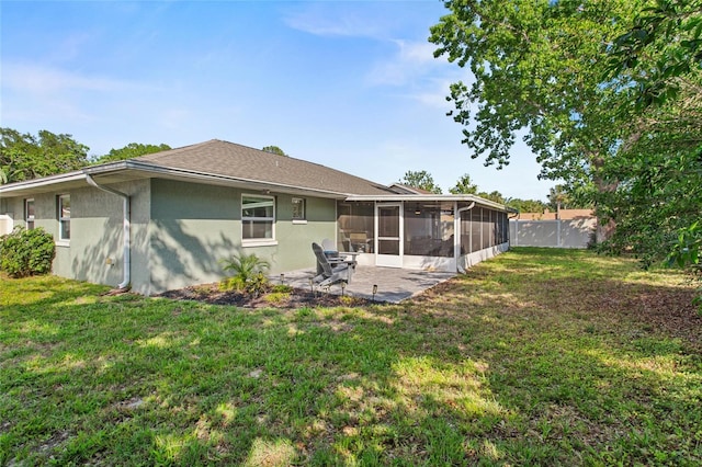 rear view of property with a lawn, fence, stucco siding, and a sunroom