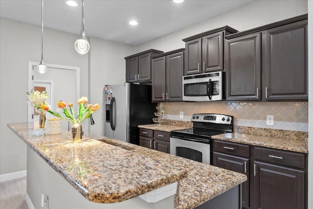 9009 Savannah Julip Ln, Orlando, FL 32832 - kitchen featuring appliances with stainless steel finishes, a kitchen island, backsplash, light stone countertops, and recessed lighting