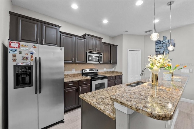 9009 Savannah Julip Ln, Orlando, FL 32832 - kitchen with stainless steel appliances, a sink, an island with sink, light stone countertops, and recessed lighting