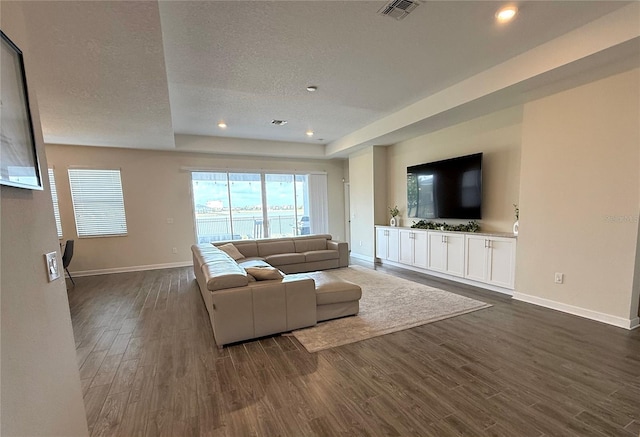 living room with visible vents, baseboards, dark wood-style floors, recessed lighting, and a textured ceiling