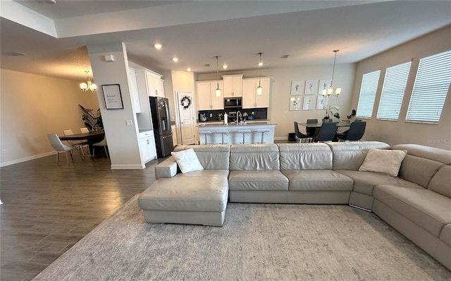 living room featuring baseboards, recessed lighting, dark wood finished floors, and a chandelier