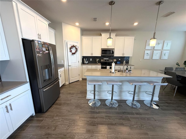 kitchen with stainless steel appliances, visible vents, pendant lighting, and dark wood finished floors