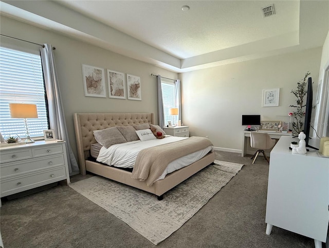 carpeted bedroom with visible vents, baseboards, and a tray ceiling