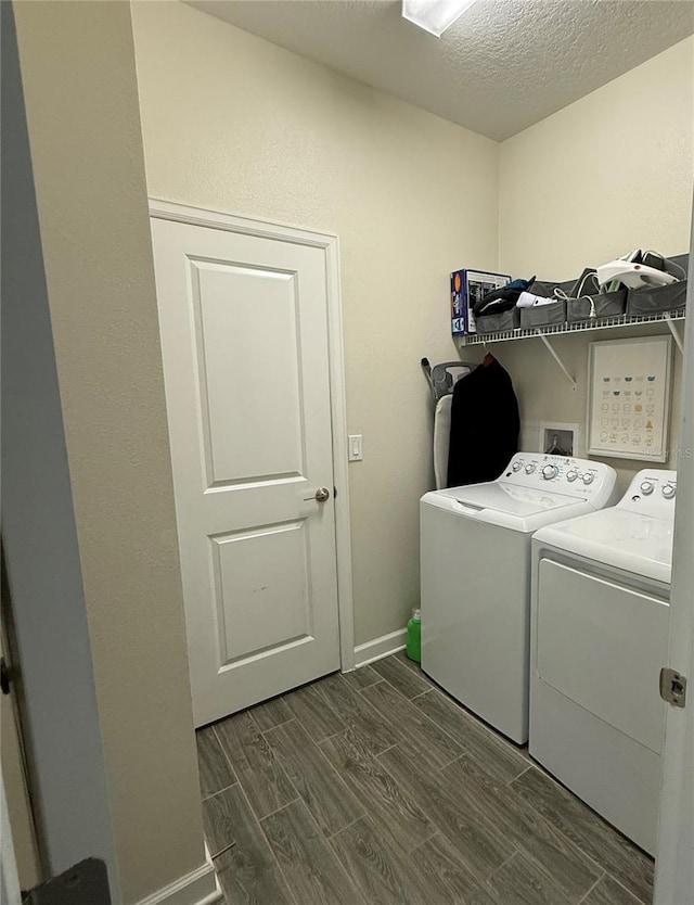 washroom with laundry area, a textured ceiling, wood finish floors, baseboards, and washer and dryer