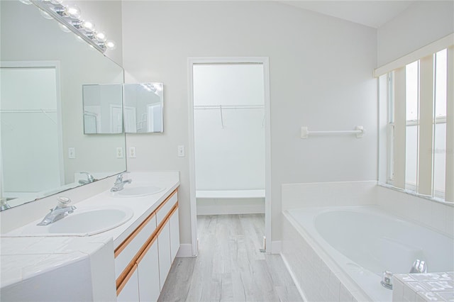 13434 Mallard Cove Blvd, Orlando, FL 32837 - full bathroom featuring a garden tub, wood finished floors, double vanity, and a walk in closet