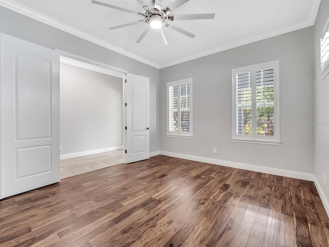 empty room featuring baseboards, ceiling fan, ornamental molding, and wood finished floors