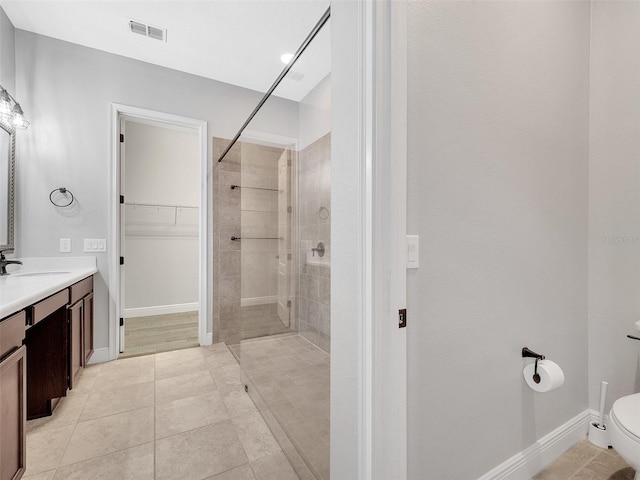 bathroom featuring a walk in closet, visible vents, a walk in shower, vanity, and toilet