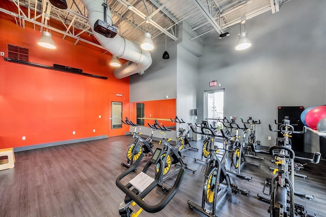 exercise room with baseboards, a high ceiling, wood finished floors, and visible vents
