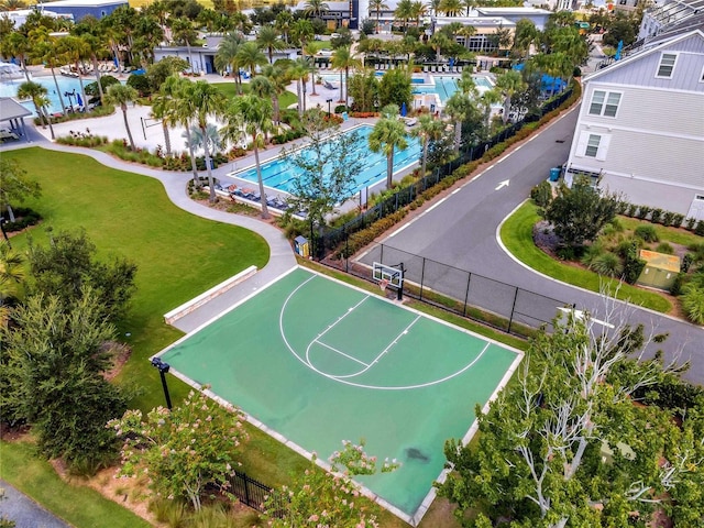 view of basketball court with fence and a lawn