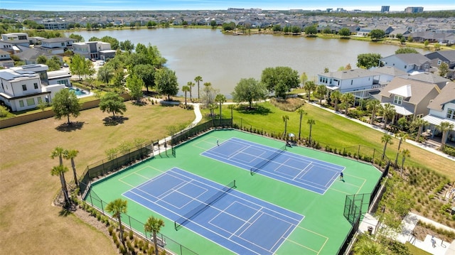 view of tennis court featuring fence, a water view, and a residential view