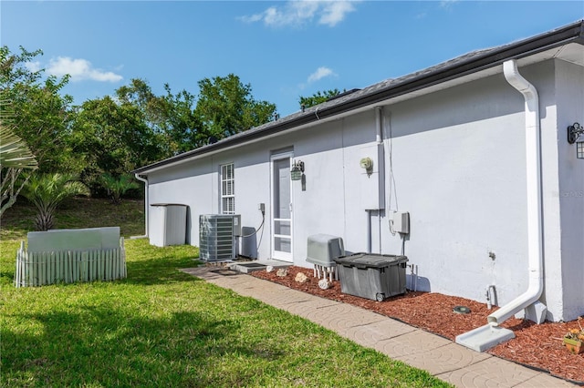 rear view of property with a lawn, stucco siding, and cooling unit