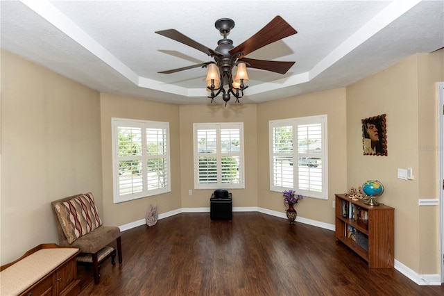 sitting room with a ceiling fan, a tray ceiling, dark wood finished floors, and a wealth of natural light