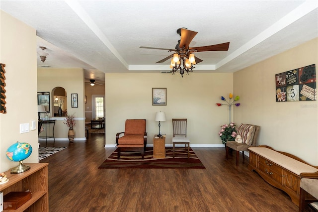 living area with a ceiling fan, baseboards, wood finished floors, and a raised ceiling